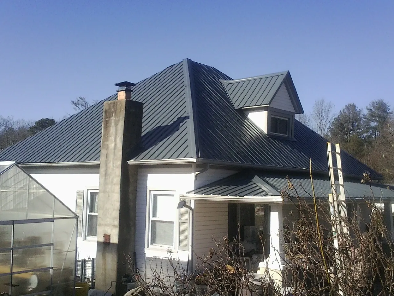 Dark blue standing seam metal roof on a white farmhouse with dormer — Slate & Tile Roof Repair by Roofing Brothers in Villa Ridge