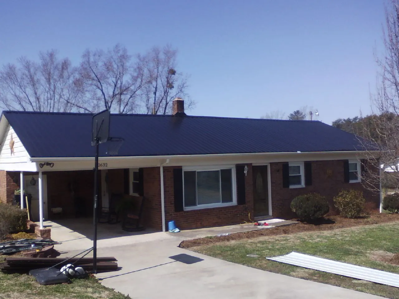 Finished dark blue metal roof on a brick ranch with a carport in Villa Ridge