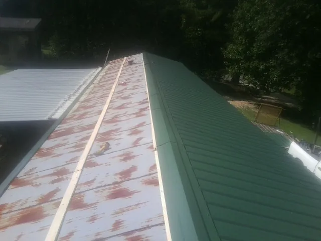 Old rusted panels beside newly installed green metal roofing — Wind Damage Roof Repair by Roofing Brothers in Villa Ridge