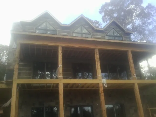Dormers and porch framing on a large log home under construction — Roof Coating work by our crew in Villa Ridge