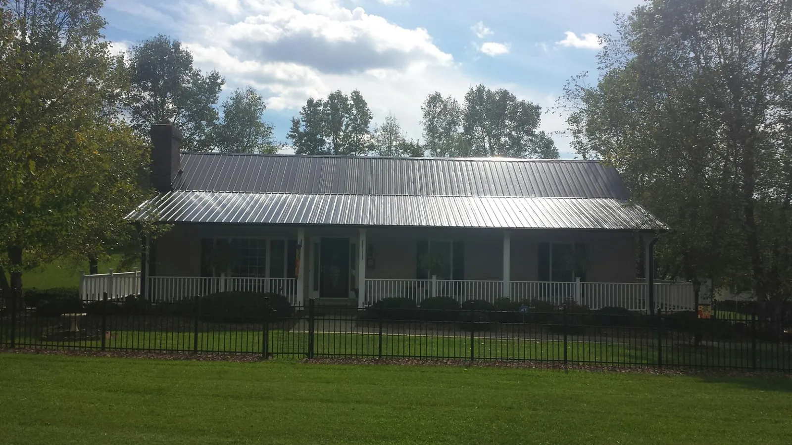 Gray metal roof on a brick ranch with a full width front porch — Gutter Guard Installation work by our crew in Villa Ridge