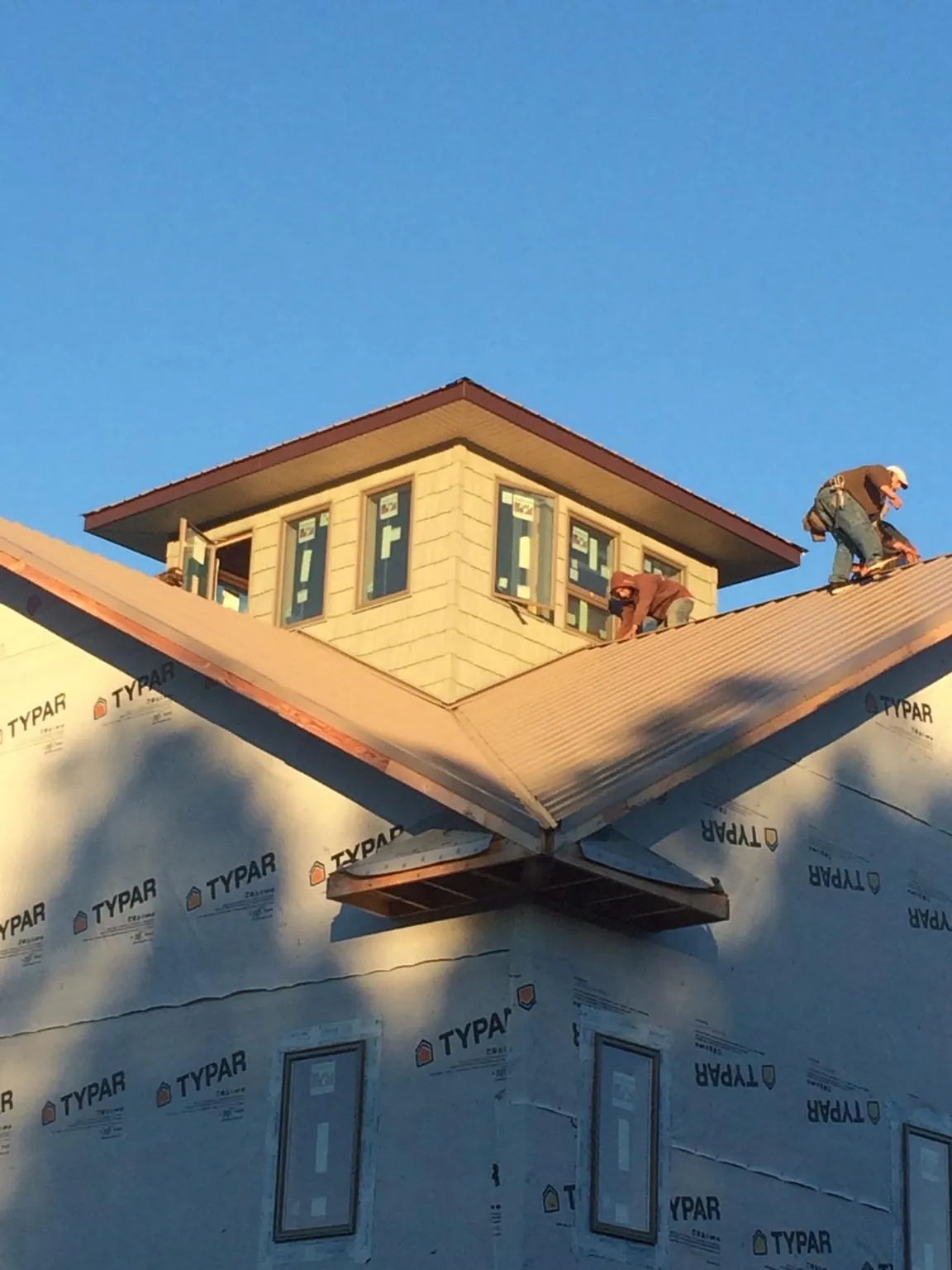 Roofers working around a rooftop cupola on a new metal roof at sunset — Roof Waterproofing in Villa Ridge by Roofing Brothers